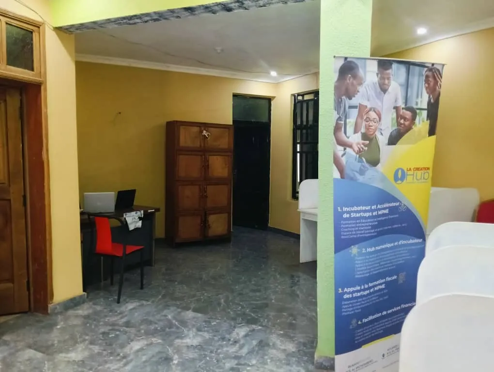 Bureau équipé d'ordinateurs à côté d'un kakémono présentant les services de LaCreation Hub.